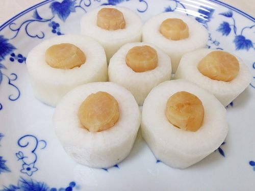 藍色花紋的大盤子裡擺著七個戳了洞又塞了干貝的切片蘿蔔